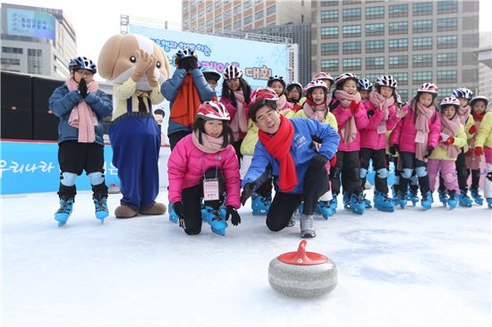 23일 이광구 우리은행장(가운데)이 서울광장 스케이트장에서 열린 '우리은행과 함께하는 신나는 스케이트 대회'에서 지역아동센터 어린이들과 컬링 체험을 하고 있다.