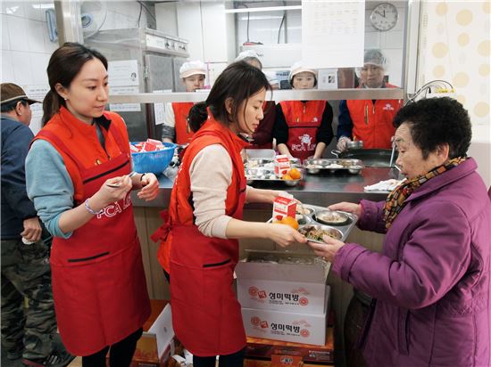 PCA생명 직원들이 서울 은평종합사회복지관에서 노인들에게 떡국과 명절 음식을 제공하고 있다.
