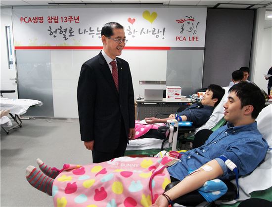 김영진 대표(왼쪽)가 '헌혈행사'에 참여해 채혈 중인 직원을 격려하고 있다.