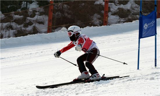 스키 대회에 참가한 어린이가 안정된 자세로 경기장을 내려오고 있다.