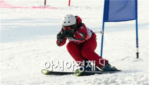 스키 대회에 참가한 어린이가 조금이라도 더 빨리 내려가려는 듯 몸을 웅크린 채 안정된 자세로 슬로프를 내려가고 있다.