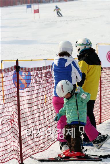 한 부부가 초등학생 스키 대회에 참가한 어린이의 경주 장면을 지켜보고 있다.
