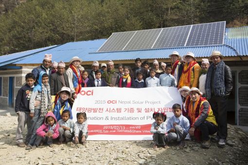 OCI 임직원 자원봉사자들이 네팔 안나푸르나 고산지역의 라트마타 마을 학교에 1.3kW 급 태양광패널을 설치하고 마을 주민들과 함께 기념사진을 찍고 있다. 