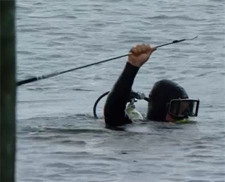 스킨스쿠버가 로리 매킬로이가 전날 물에 던진 3번 아이언을 꺼내고 있다. 사진=미국 골프채널 캡처.