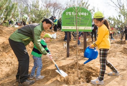 서강호 이브자리 대표(왼쪽)가 28일 서울 강동구 둔촌동 일자산도시자연공원에서 열린 '서울시와 이브자리가 함께하는 탄소상쇄숲 조성행사'에서 참여 아이들과 나무를 심고 있다.