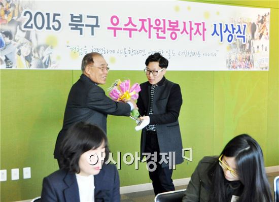 전남대학교 미담장학회 우수환 회장(오른쪽)이 3월25일 김용선(왼쪽) 광주북구종합자원봉사센터 이사장으로부터 2015우수자원봉사자상 상패와 꽃다발을 받고 있다.