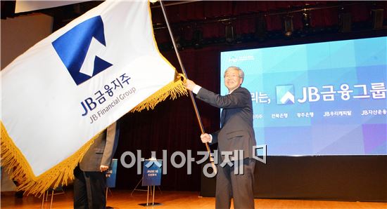 JB금융지주 김한 회장이 3일 열린 JB금융그룹 통합 CI 선포식에서 새로운 통합 CI가 새겨진 깃발을 힘차게 흔들고 있다. 