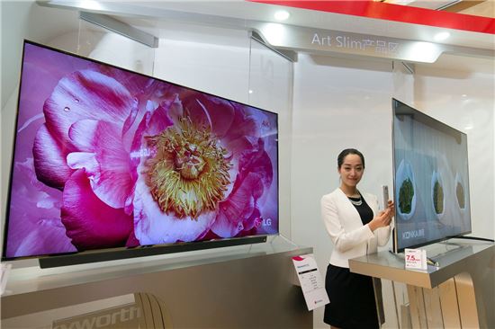 15일(현지시간) 중국 베이징에서 열린 LG디스플레이의 '아트슬림 프로모션'행사에서 도우미가 전시된 아트슬림 TV와 스마트폰 두께를 비교하고 있다.