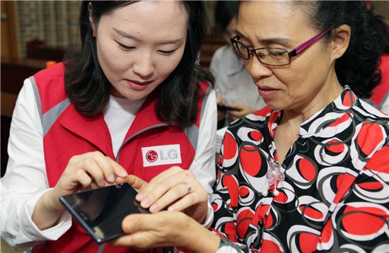 LG전자 직원이 시각장애인에게 책 읽어주는 휴대폰 사용법을 알려주고 있다. (사진제공 : LG)