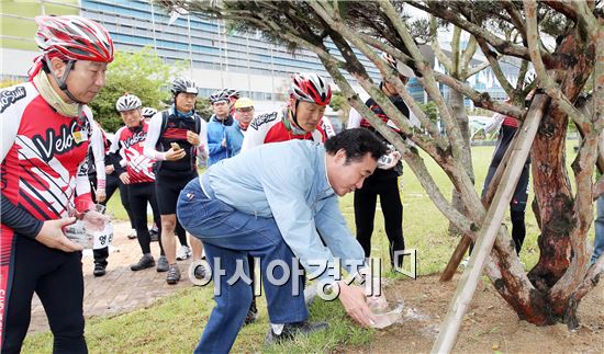 이낙연 도지사가 3일 오전 전남도청 광장에서 열린 전라남도-경상북도 공무원 상생화합 영산강길 자전거 종주 합수식(영산강물ㆍ낙동강물)에서 합수된 물을 나무에 뿌려주고 있다. 사진제공=전남도