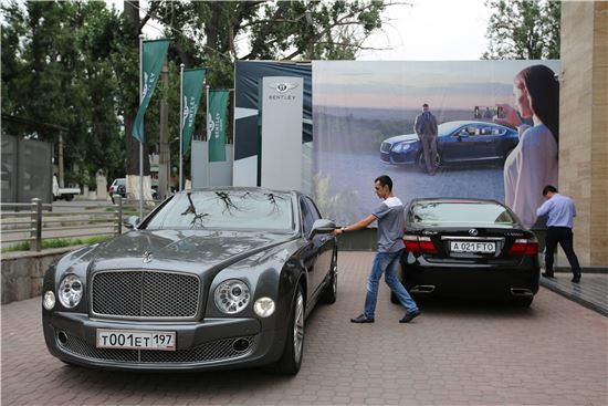 카자흐스탄 알마티의 벤틀리 모터스 매장에서 신형 모델들을 살펴보고 나온 한 남성이 자기가 이미 갖고 있는 벤틀리 자동차에 오르려 하고 있다(사진=블룸버그뉴스).