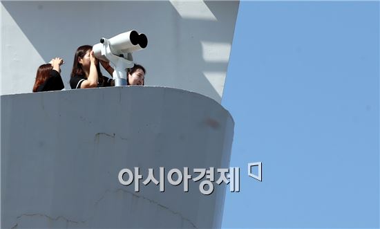 6일 더위를 피해 전남 함평군 함평읍 돌머리해수욕장을 찾은 관광객들이 전망대에서 관찰 망원경을 들여다보며 바다를 감상하고 있다.  함평군은 최근 돌머리해변이 내려다보이는 전망대에 조류와 갯벌체험을 관찰할 수 있는 망원경을 설치했다. 사진제공=함평군
