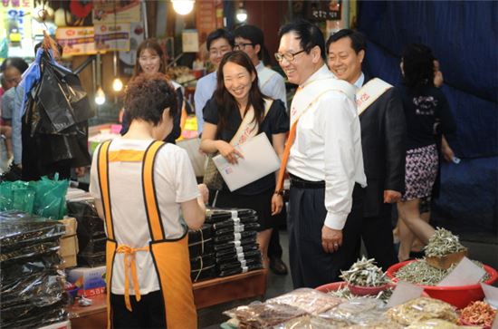 이규택 한국교직원공제회 이사장이 경기인천지역본부 직원들과 25일 수원시 팔달구 못골시장을 찾아 직접 물품을 구입하며 전통시장 이용 활성화를 위한 길거리 캠페인을 진행 중이다. 
