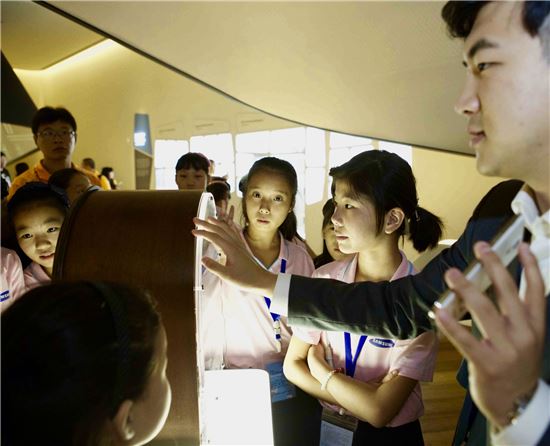 한국을 방문한 중국 삼성희망소학교 어린이들이 수원 삼성전자 홍보관에서 휴대폰의 역사에 대한 설명을 듣고 있다. 