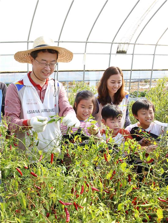 아시아나항공 김수천 사장(왼쪽에서 네번째)이 봉사활동에 참가한 임직원 자녀들과 수확한 벼를 직접 옮기고 있다.
