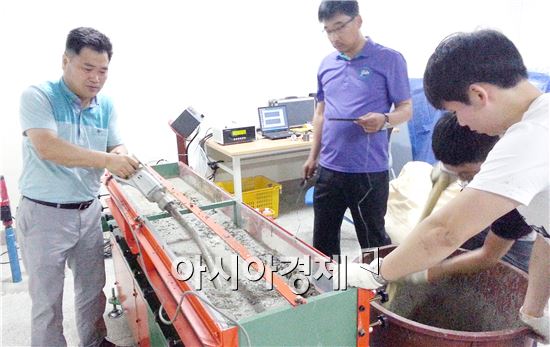 국내 건설기술 향상에 기여할 수 있는 '포장진동시험장치(Pavement Shaking Table, PST)'를 개발한 토목환경공학과 정제평 교수가 학생들과 함께 내구성 있는 포장콘크리트의 비율을 위한 콘크리트 배합 실험을 하고 있다.