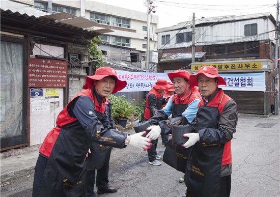6일 김문경 대한주택건설협회장(사진 오른쪽)이 서울 용산구 백범로 99가길 12 일대에서 연탄나눔 봉사활동을하며 기념촬영을 하고 있다.

