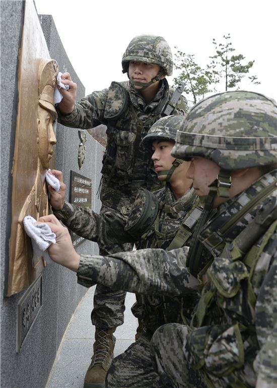 연평도포격전을 맞아 진행되는 훈련으로 인해 전역까지 연기한 연평해병 3인방(왼쪽부터김성우,설정호,이원규병장)이 연평도 평화공원에서 고(故)서정우하사 부조를 닦고 있다. (사진제공=해병대)