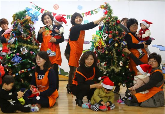 한화생명 맘스케어 봉사단원들이 명진들꽃사랑마을에서 아이들과 함께 크리스마스 트리를 장식하고 있다. 