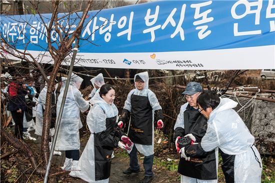 문규영 아주그룹 (오른쪽 두번째)과 임직원들이 서울 남태령 전원마을 지역사회 이웃들의 따뜻한 겨울나기를 위한 ‘사랑의 부싯돌’ 현장에서 줄지어 연탄을 나르고 있다.
