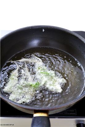 4. 냉이를 180℃의 튀김기름에 튀긴다.
(Tip 냉이는 익지 않아도 먹을 수 있는 재료라 튀김옷이 바삭하게 익으면 바로 건져 체에 담아 기름을 뺀 후 접시에 담는다. )

