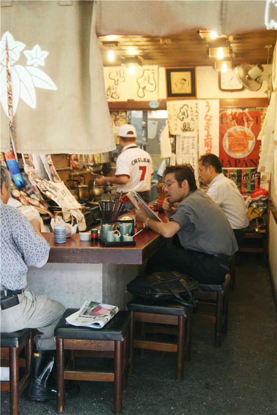 대부분의 관광객들은 수산시장의 명물 초밥을 먹기 위해 초밥집 앞에 몰려들지만 시장 사람들은 관광객들을 피해 그들만의 밥집으로 몰려간다.