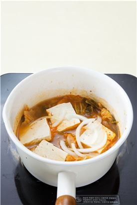 4. 김치가 부드럽게 익으면 양파와 두부를 넣고 끓이다가 풋고추, 홍고추, 대파, 다진 마늘을 넣어 살짝 끓이고 소금과 후춧가루로 간한다. 
