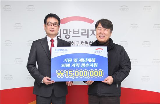 오비맥주 장유택 전무(좌측)가 15일 서울 마포구 희망브리지회관에서 박영진 사무총장에게 수해지역 이재민들의 식수지원을 위한 기부금을 전달하고 있다.
