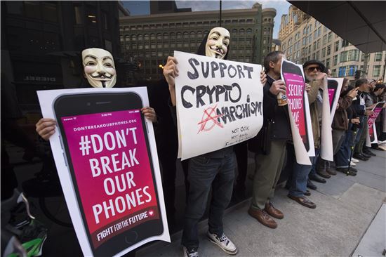 23일(현지시간) 캘리포니아의 애플스토어 앞에서 가면을 쓴 사람들이 팻말을 들고 FBI가 애플에 아이폰 잠금장치를 풀라고 요구하는 것에 대한 항의집회를 벌이고 있다.  (샌프란시스코 = EPA연합뉴스)