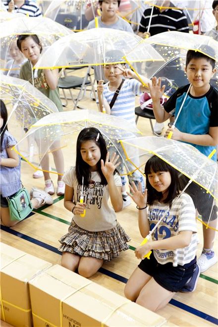 어린이 투명우산을 받은 어린이들이 활짝 웃고 있다. 