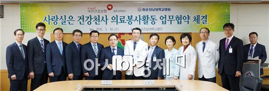 김형준 화순전남대병원장(왼쪽에서 7번째)이 김백수 국민건강보험공단 광주본부장(왼쪽에서 6번째)과 의료봉사활동 강화를 약속하는 협약서를 들어보이고 있다.