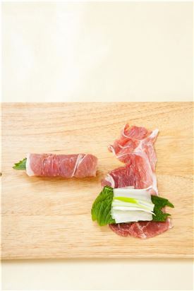3. 돼지고기 위에 깻잎을 펼쳐서 나란히 깔고 그 위에 대파를 놓은 다음 김밥 말듯이 돌돌 만다.
