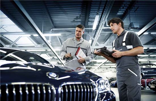 BMW 엔지니어들이 자동차를 둘러보면서 이야기를 나누고 있다.