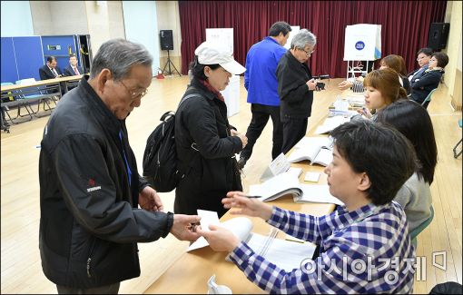 13일 오전 투표장을 찾은 사람들이 신분을 확인하고 투표용지를 받고 있다.