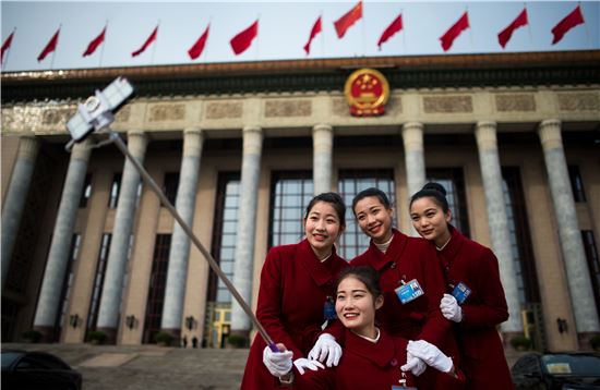지난 3월 6일(현지시간) 중국의 젊은 여성들이 베이징(北京) 인민대회당 앞에서 활짝 웃는 얼굴로 셀카 촬영에 여념이 없다. 베이징(중국)=AFP연합뉴스