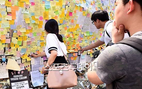 시민들이 강남역 사건의 피해자를 추모하는 포스트잇을 강남역 10번 출구에 붙이고 있다.
