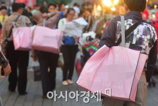 중국 관광객들이 쇼핑한 물건을 어깨에 메고 명동거리를 걷고 있다.