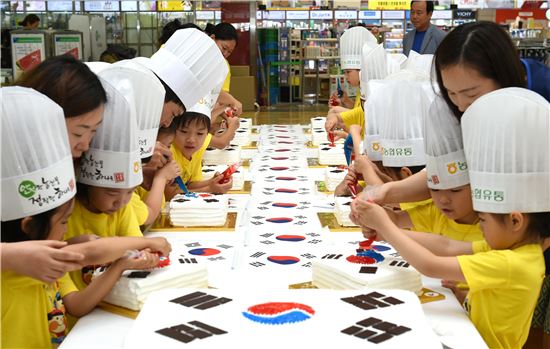 31일 호국보훈의 달을 맞아 서울 서초구 농협하나로클럽 양재점에서 어린이들이 쌀케이크 위에 태극기를 만들고 있다.