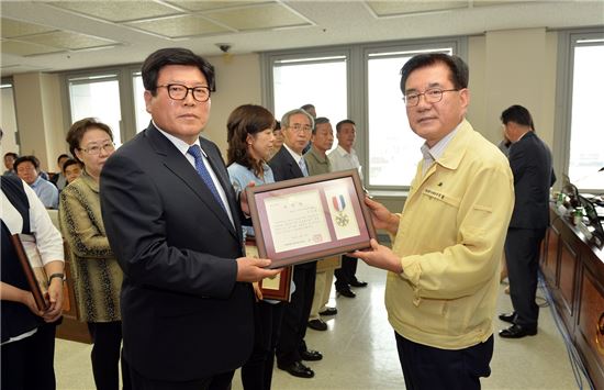 유덕열 동대문구청장(오른쪽)이 6월 23일 확대간부회의에서 김두용 씨에게 표창을 수여하고 있다.
