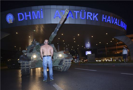 16일(현지시간) 웃옷을 벗은 한 시민이 터키 이스탄불의 아타튀르크 국제공항을 막아선 탱크를 바라보고 있다.(AP=연합뉴스)  