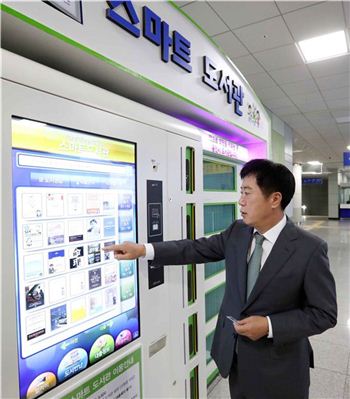 정찬민 용인시장이 기흥역 무인 스마트 도서관을 찾아 책 대출 시연을 하고 있다.