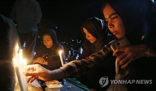 23일 아프가니스탄 수도 카불에서 여성들이 80명이 사망한 IS의 자폭테러 희생자들을 추모하며 촛불을 밝히고 있다. 사진=연합뉴스 제공
