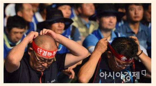 금속노조 조합원들이 지난 22일 서울 종로구 광화문 광장에서 열린 총파업에 참여해 머리띠를 고쳐메고 있다.