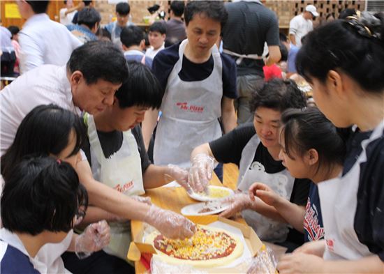지난 13일 안산 동산교회에서 열린 안산지역 장애아동 여름수련회에서 참가자들이 미스터피자의 드림팀과 피자를 만들어보고 있다.