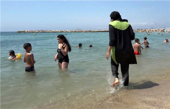 ▲부르키니를 입고 물 속에 들어가는 여성(오른쪽). (AP=연합뉴스)