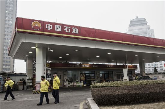 ▲중국 국영 석유업체 시노펙이 운영하고 있는 베이징 시내 한 주유소에서 직원들이 이야기를 나누고 있다. 시노펙을 포함한 석유업계 부진이 길어지면서 구조조정설이 흘러나오고 있다. (사진=블룸버그)