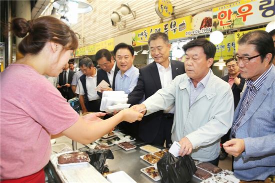 박성택 중소기업중앙회 회장(오른쪽 두번째)이 경기도 군포시 산본시장을 방문해 상점에서 떡을 구매하고 있다.  