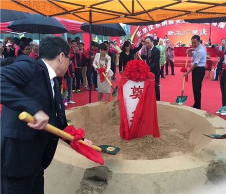 경동나비엔의 중국 베이징 신공장 기공식에 참석한 관계자들이 삽으로 흙을 떠 넣고 있다. 