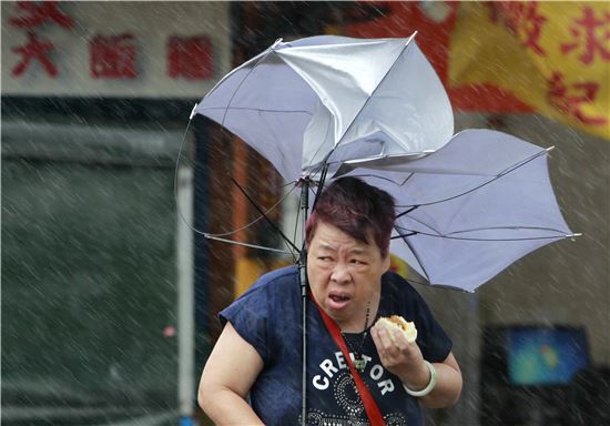 한 대만 여성이 태풍 메기로 인한 비바람 속에서도 손에든 음식을 먹으며 어딘가 바라보고 있다.(사진=AP연합)