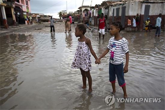 지난 6일(현지시간) 허리케인 매슈가 강타한 아이티의 서남 해안 항구도시 레카예스에서 물이 발목까지 차오른 거리를 아이들이 걷고 있다.(사진출처=AP연합)